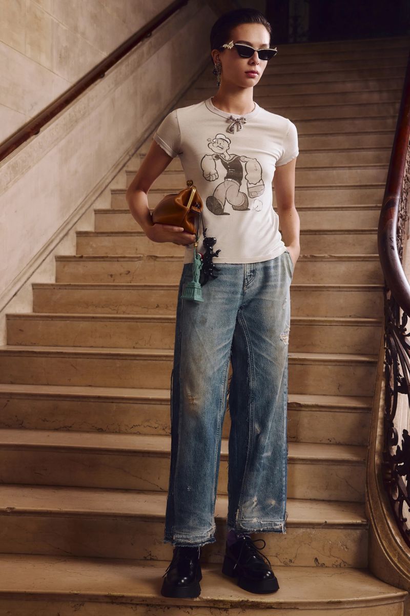 Young woman in trendy casual fashion posing on stairs. She's wearing a t-shirt, wide leg jeans, and black patent leather platform shoes.