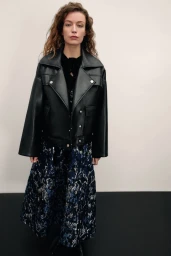 Model Hazel Jane in an oversized black leather jacket and patterned midi dress against a plain studio background.
