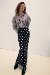 Model wearing a striped blouse and polka dot skirt against a plain studio background for Tanya Taylor