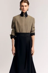 Model wearing a structured brown jacket and dark belted skirt against a seamless grey background for Lanvin Resort 2025 lookbook