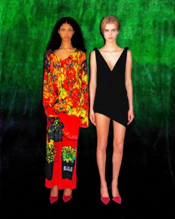 Two women in stylish dresses and pink heels pose against a vibrant green and black backdrop, creating a bold fashion statement.