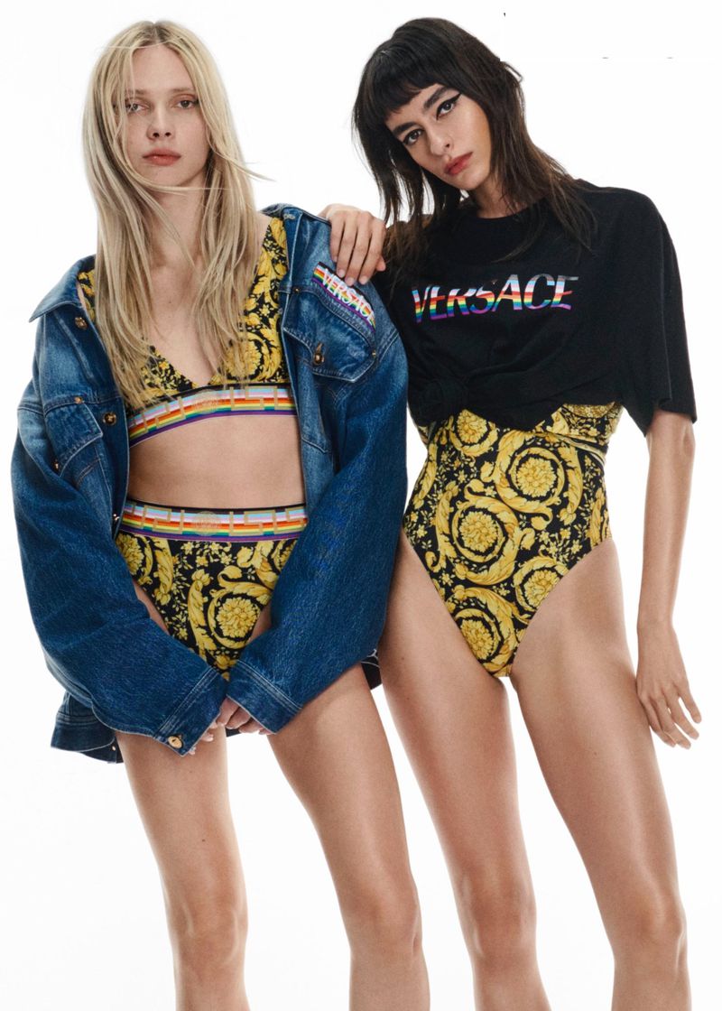Two fashion models wearing Versace apparel in a studio setting. One poses in a bra top and jacket, the other in a t-shirt and bottoms.