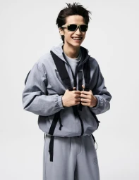 Model Brad Lee smiling in a grey hooded zip-up jacket and sunglasses against a plain white studio background.