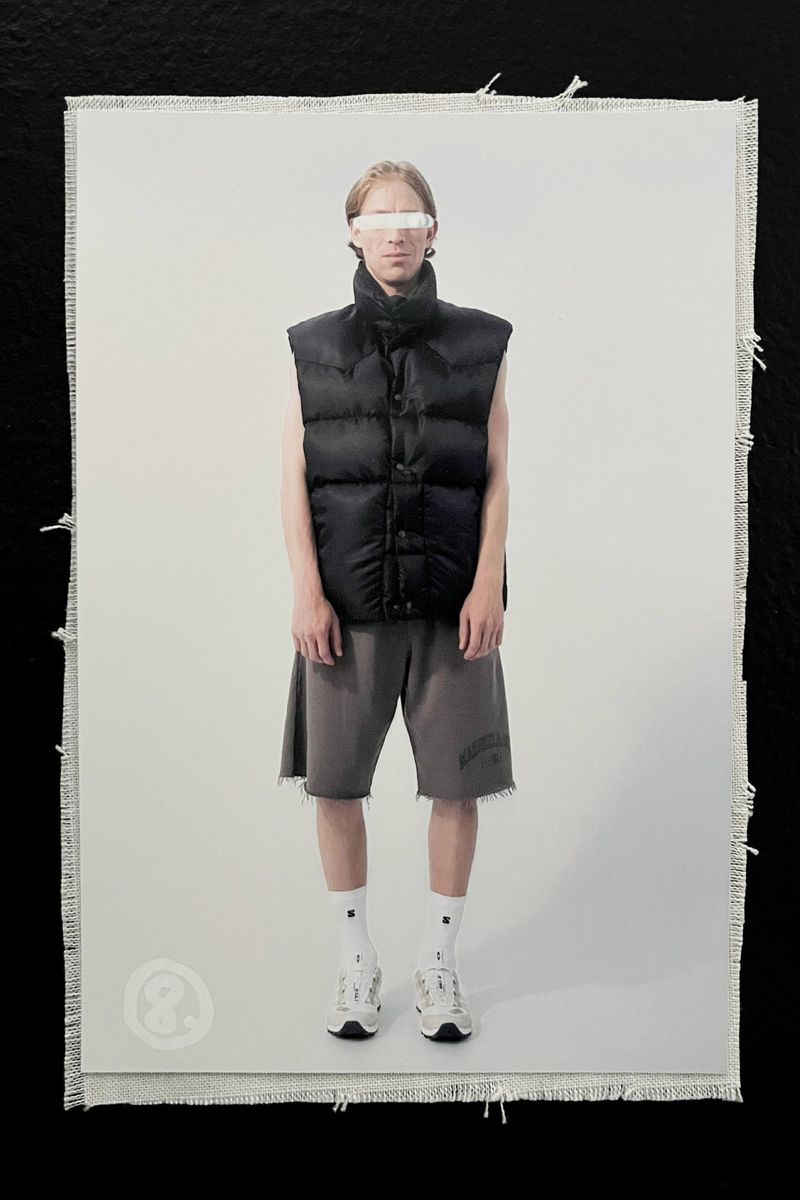 Studio shot of a person wearing a black puffer vest, gray shorts, white socks, and white sneakers, against a white background.