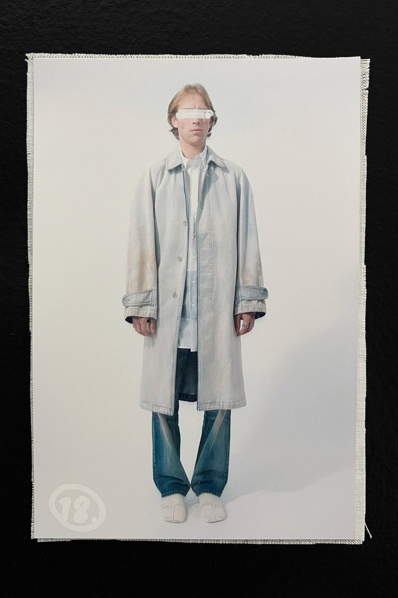 Fashion shot of a person wearing a long coat and jeans against a white background, captured in a studio setting with neutral colors.