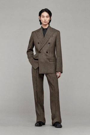 An Asian man wearing a patterned double-breasted suit is posing indoors. He has a neutral expression and is looking at the camera.