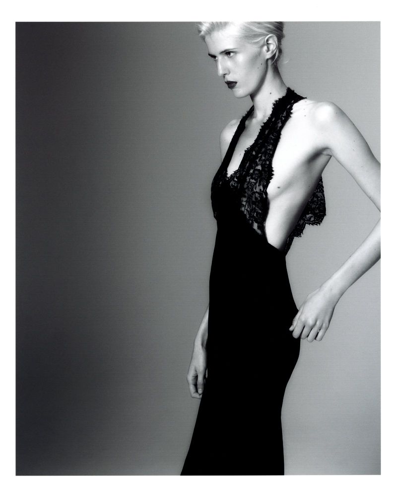 Model wearing a black lace dress against a grey studio backdrop