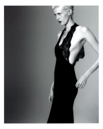Model wearing a black lace dress against a grey studio backdrop