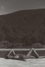 Model lying on stone ground outdoors against a hill backdrop for the Anthropologie Linen project.
