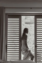 Model standing by a slatted door wearing a patterned linen dress for Anthropologie