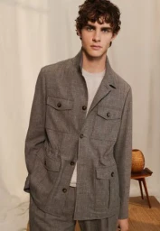 Model wearing a grey textured utility jacket with four front flap pockets against a neutral backdrop.