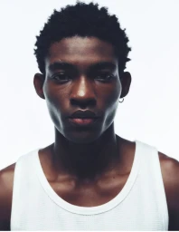 Close-up portrait of a Black male model wearing a white tank top against a plain white background