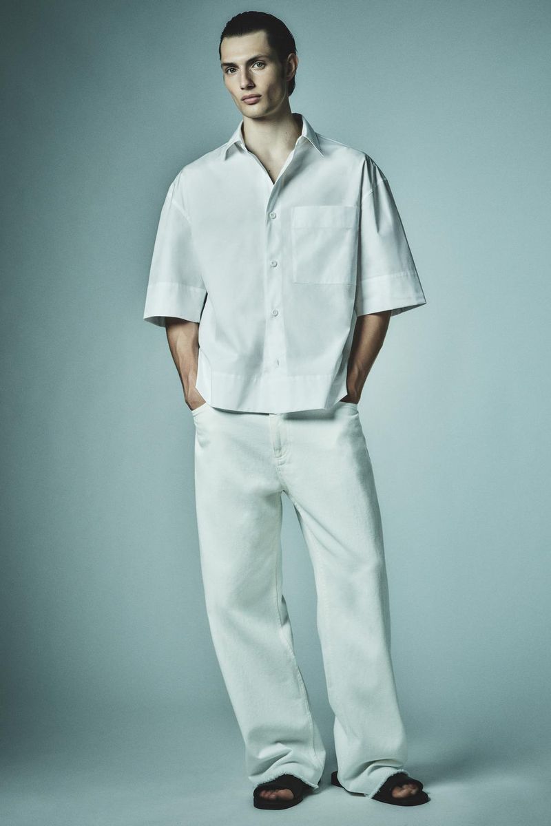 Thatcher Thornton wearing a white short-sleeve linen shirt and matching wide-leg trousers against a soft studio backdrop.