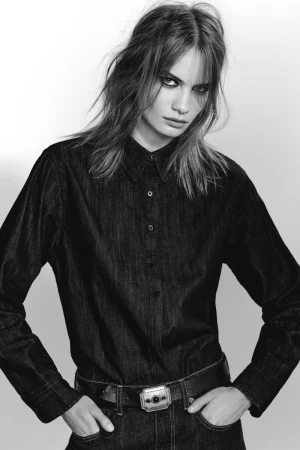 Model Nina Marker in a dark denim shirt and belt against a plain white studio background for Zara, photographed by Collier Schorr.