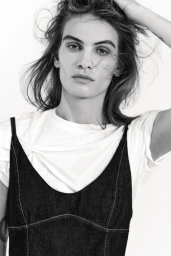 Close-up portrait of model Nina Marker wearing a dark denim slip dress over a white t-shirt against a plain background.