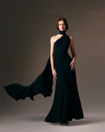Model Lydia Waldrop wearing a dark flowing cape gown in a studio portrait for the Alexis Mabille Fall 2024 Couture Lookbook.
