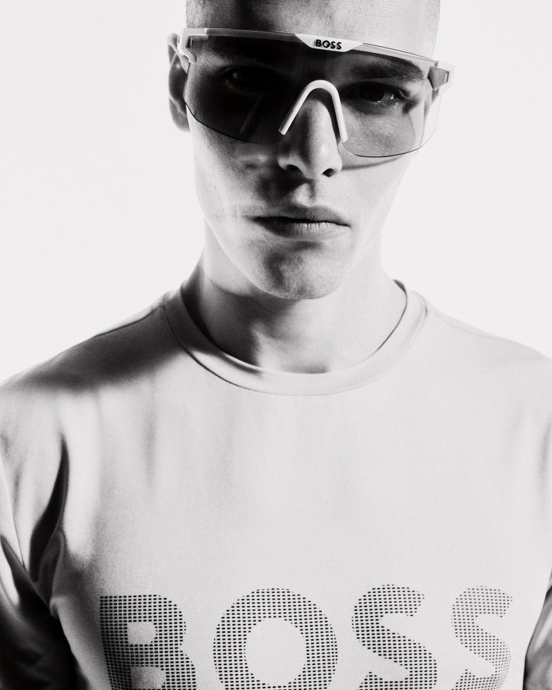 Rafael Mayers wearing futuristic BOSS shield sunglasses and a white logo t-shirt in a black and white portrait.
