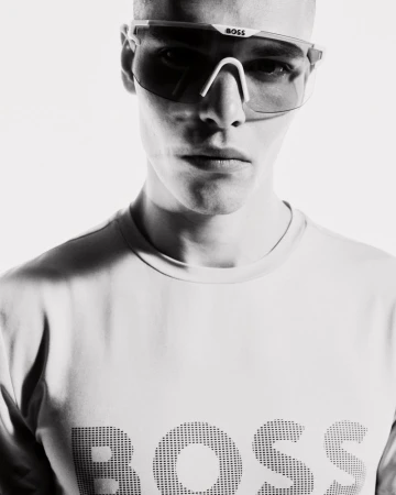 Rafael Mayers wearing futuristic BOSS shield sunglasses and a white logo t-shirt in a black and white portrait.
