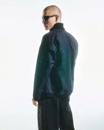 Model Rafael Mayers wearing a dark iridescent jacket and wraparound sunglasses against a bright white background.