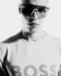 Rafael Mayers wearing futuristic BOSS shield sunglasses and a white logo t-shirt in a black and white portrait.