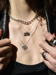 Close-up portrait of a model wearing layered silver necklaces and chunky rings with a black leather jacket for Knowhow Jewelry.