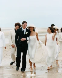 Group of models in white and black wedding attire walking on a sandy beach for the Jacquemus bridal campaign.