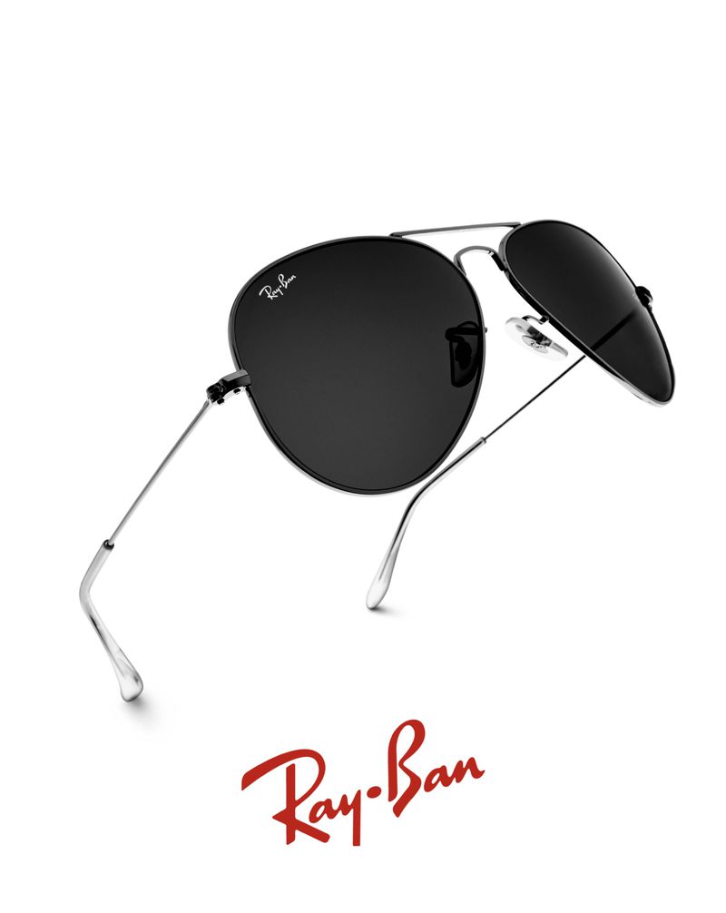 Ray-Ban aviator sunglasses with black lenses and silver frames are angled on a white background, reflecting light.