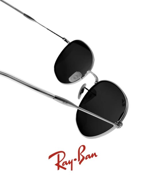 Eye-level studio shot showcasing Ray-Ban sunglasses with dark lenses and silver frames, against a clean white background with the brand logo.