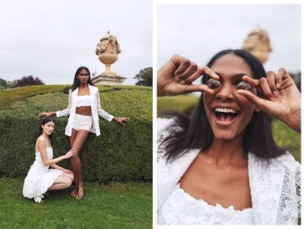 Two female models in white lace outfits posing outdoors near a sculpted urn in a garden setting for Emanuel Ungaro