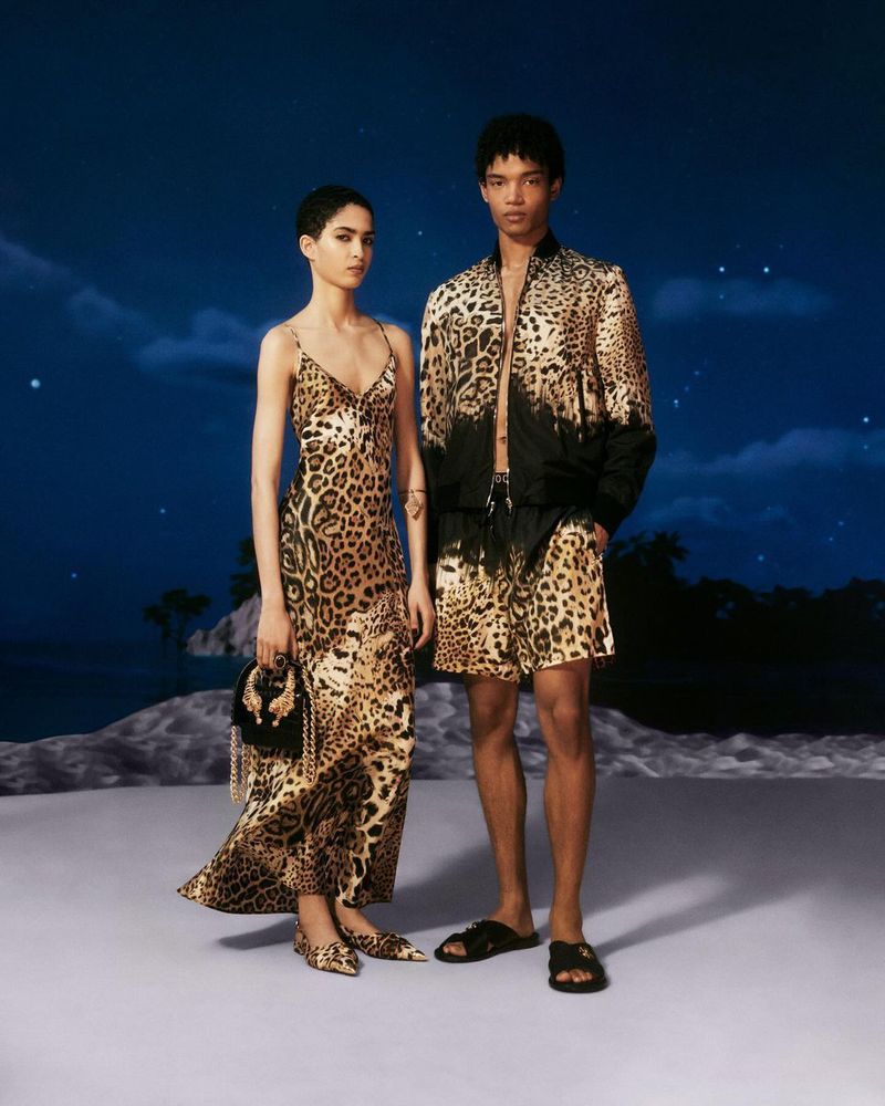 Two fashion models, an adult female and an adult male, posing in a photo studio setting wearing leopard print outfits.