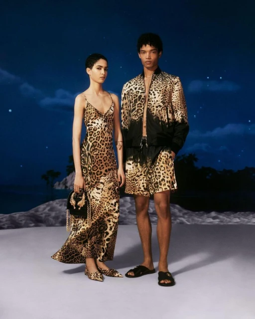 Two fashion models, an adult female and an adult male, posing in a photo studio setting wearing leopard print outfits.