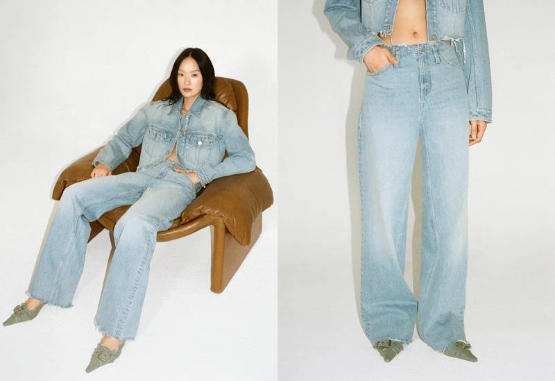 A woman sits in a brown leather chair, wearing a light blue denim jacket and flared jeans against a white backdrop in a fashion shoot.