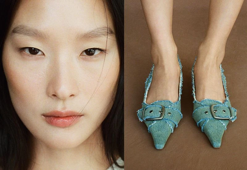 Close-up of a stylish adult woman with fair skin and dark hair, alongside a pair of denim heeled shoes with metallic buckles on a brown background.