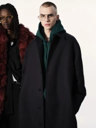 Two models posing against a white background, wearing dark coats and layered casual apparel in a lookbook fashion portrait.