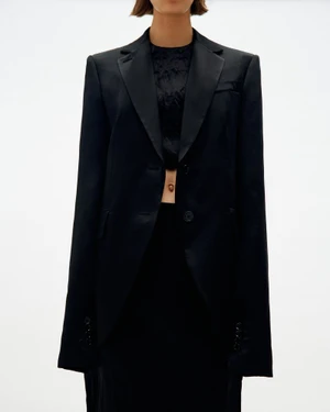 Model wearing a structured black blazer and dark top against a white background for Sportmax