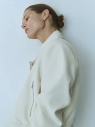 Model Malgosia Bela wearing an off-white jacket against a plain light background for Mango