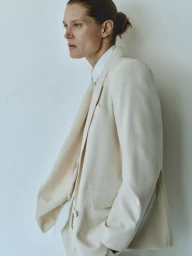 Model Malgosia Bela wearing a cream blazer and white shirt against a neutral background