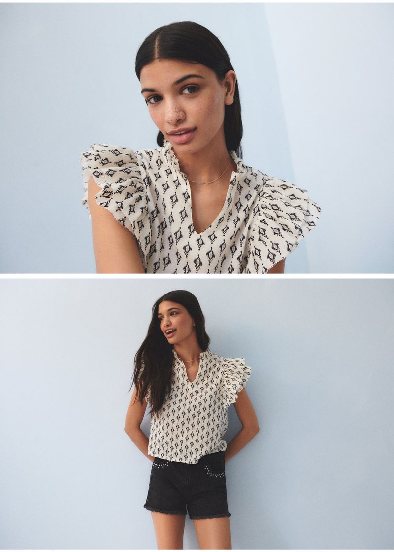 Portrait of a woman in a patterned top and black shorts against a light blue background, fashion photography, studio shot.