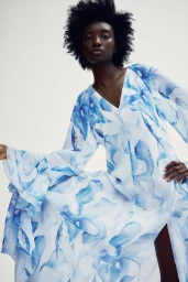 Model wearing a white and blue floral print dress against a plain white studio background