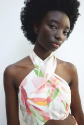 Portrait of a Black woman wearing a floral print halter neck dress against a white background for H and M