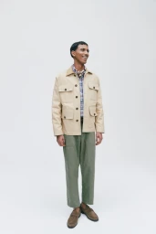 Model Mohamed Hassan wearing a tan utility jacket and green trousers against a clean white backdrop for Nordstrom