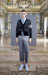 Model wearing a patterned cardigan and grey trousers standing in an ornate hall for Thom Browne S/S 24