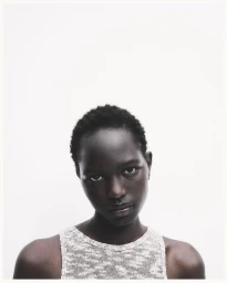 Model Nyaduola Gabriel wearing a sleeveless textured knit top against a seamless white studio background.