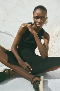 Model Janelle Ononye seated in black attire and espadrilles against a marble background, photographed by Lala Serrano.