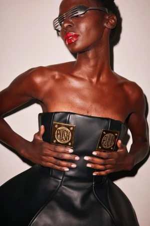 Adult woman poses wearing a black dress with gold accents and a pair of repurposed fork sunglasses with red lipstick and neutral background.