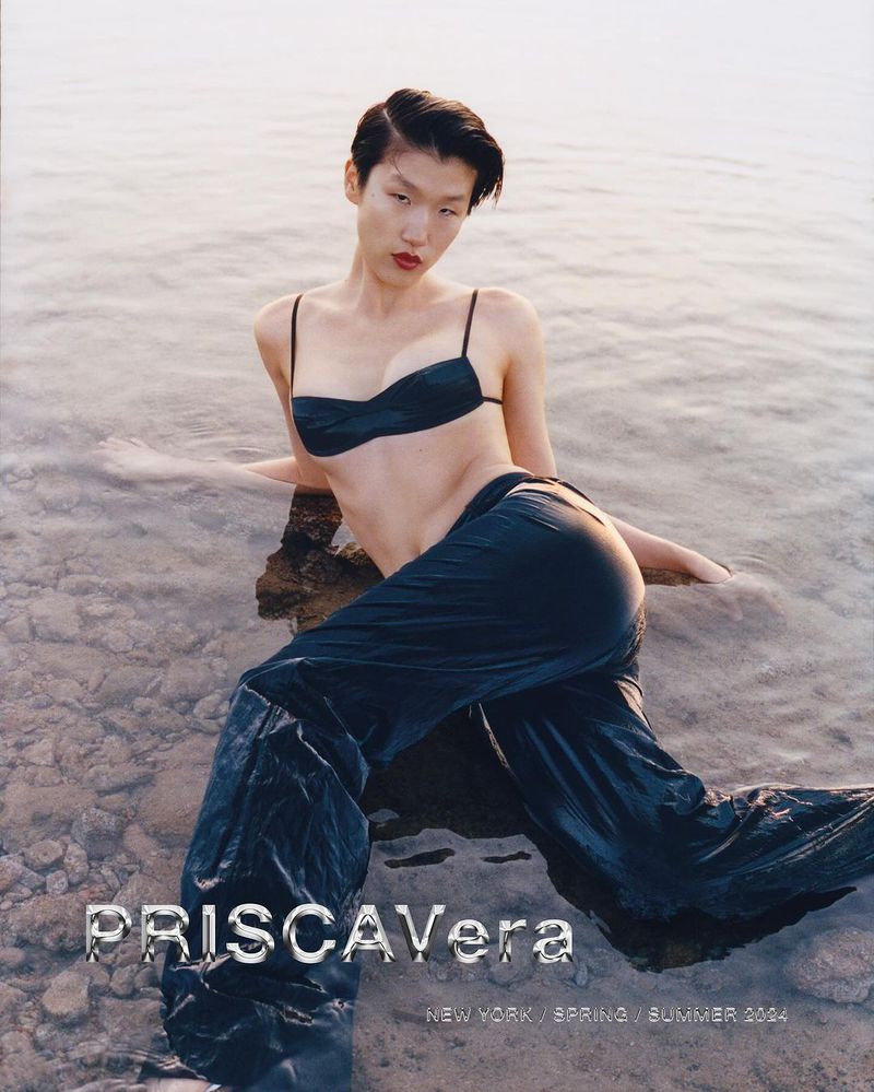 Fashion shot of a woman in a bikini top and pants reclining in water, with fashion branding visible at the bottom of the image.