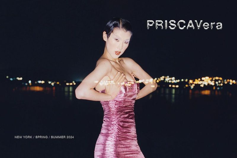 Model Jiashan Liu wears a metallic pink strapless dress against a dark body of water with blurred city lights at night.