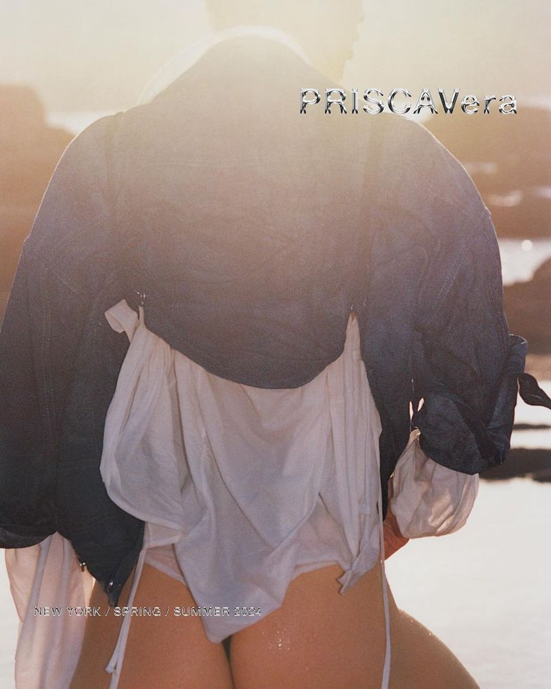 Blonde woman in wet white swimsuit stands on the beach in front of the ocean. Magazine cover shoot for PriscaVera Spring/Summer 2024.