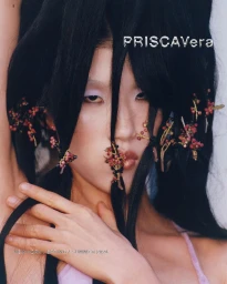 Close-up portrait of model Jiashan Liu with berry sprigs woven into long black hair for PRISCAVera Spring/Summer 2024.