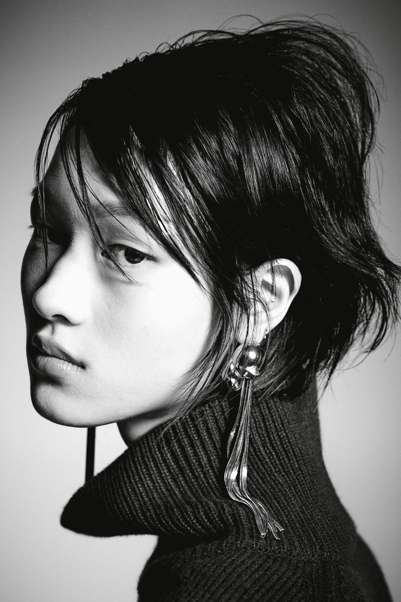 Portrait of a stylish woman in a turtleneck sweater and dangling earrings. Black and white fashion headshot with soft light.
